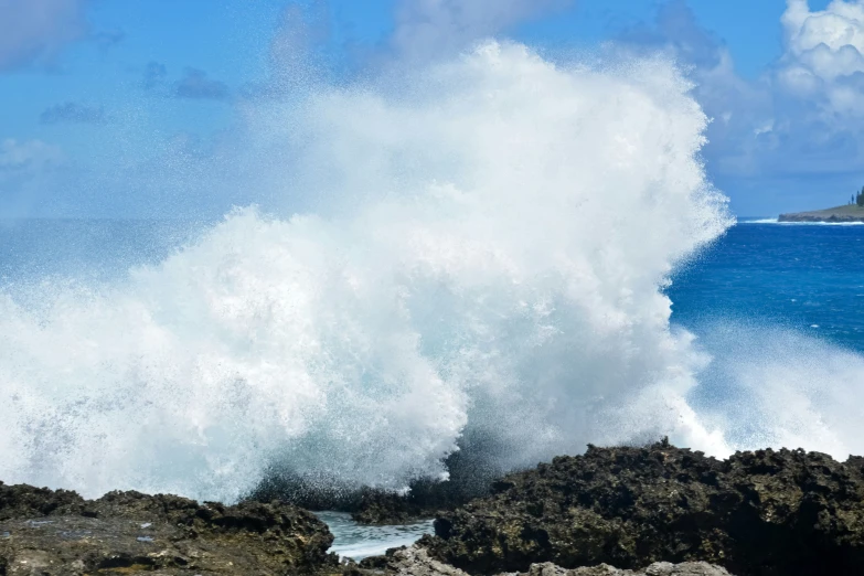 a large wave crashes on the rocks while standing by the ocean