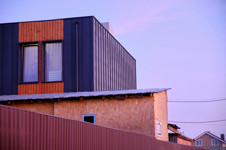 a red brick building with a fence and metal roof