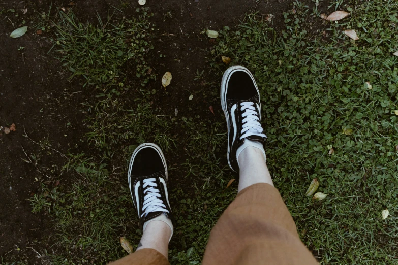 a person is standing on the ground with white sneakers