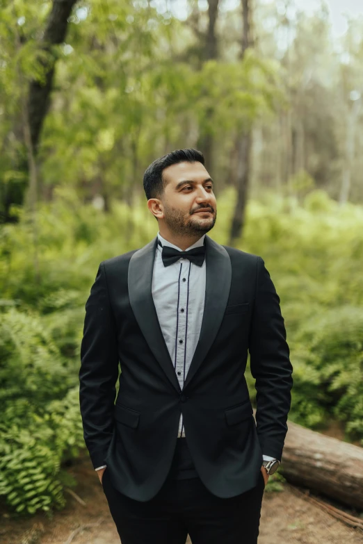 man wearing a black suit and bow tie poses for a po