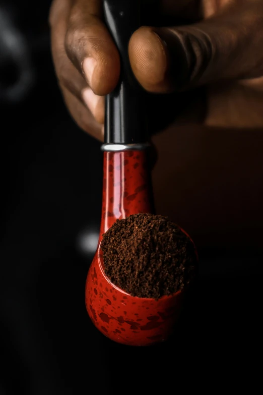 a person holding a coffee grinder and brown powder