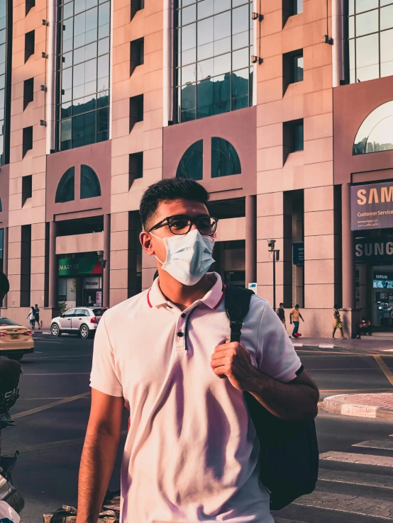 a man with glasses wearing a mask stands on the street