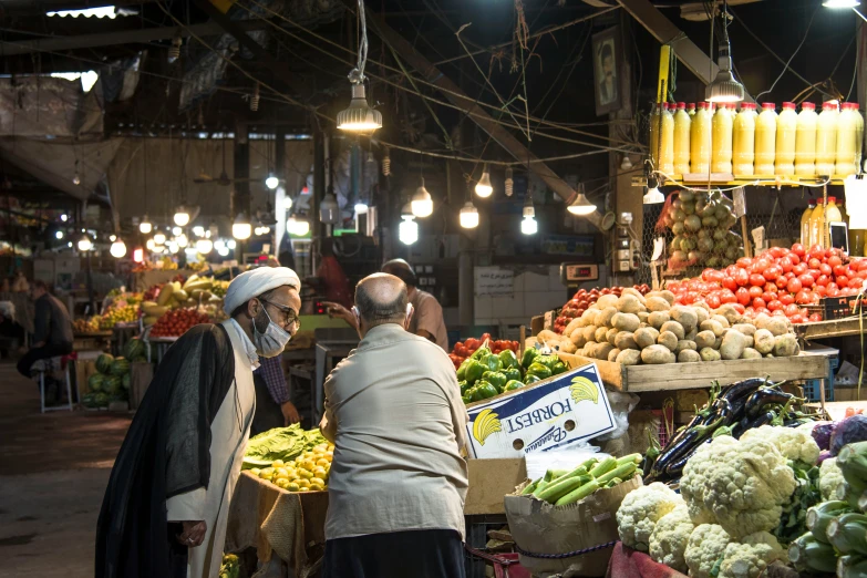 two men at a market looking at vegetables and fruits