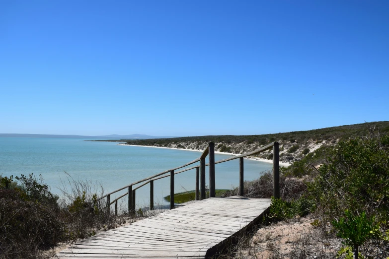 a wooden boardwalk extending from the beach to the sea