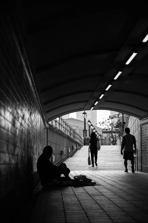 people are standing and sitting under a train station