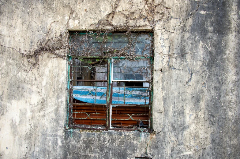 a rusted out wall is seen with an old window on the outside