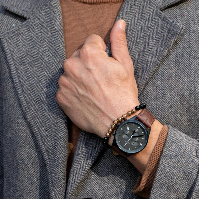 a hand with a brown wrist celet with some sort of watch