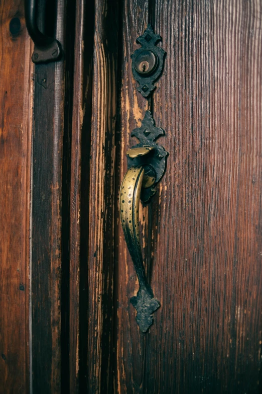 an iron handle on a wooden door on a wooden surface