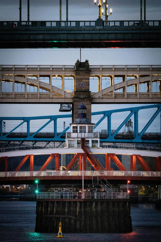 a red and white tugboat in front of a blue bridge