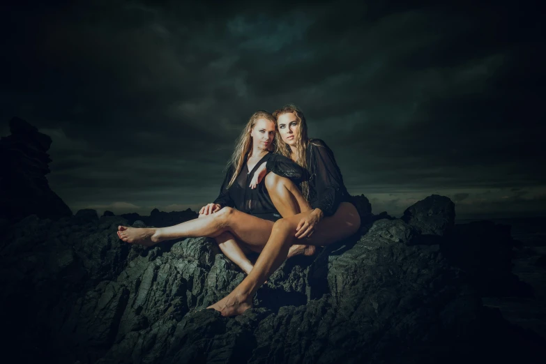 two women sitting on some rocks at night