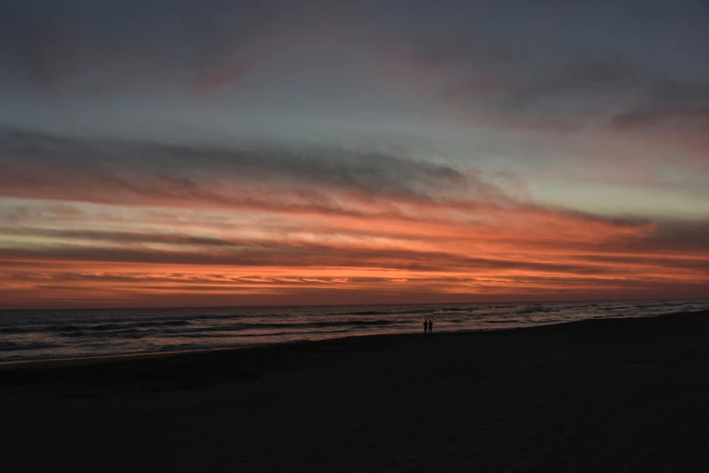 there is a person walking down the beach and some waves are in the water