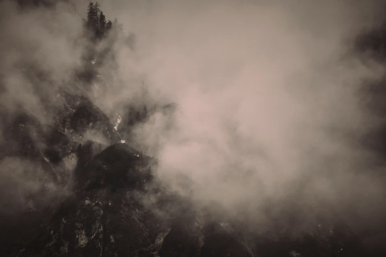 a very dark and foggy mountain scene with trees