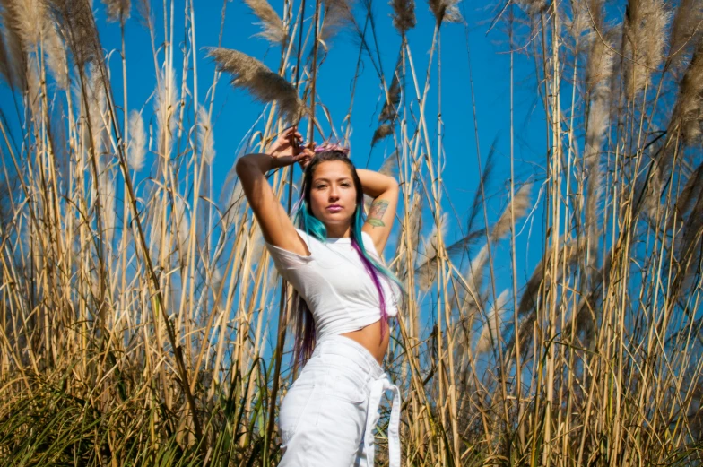 the woman poses with her hair in front of tall grass