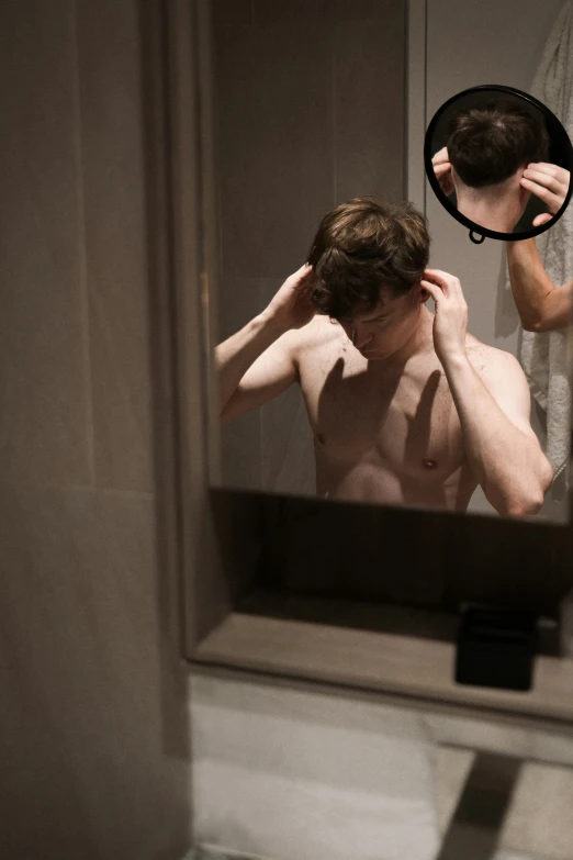 a man in  standing near a bathroom mirror