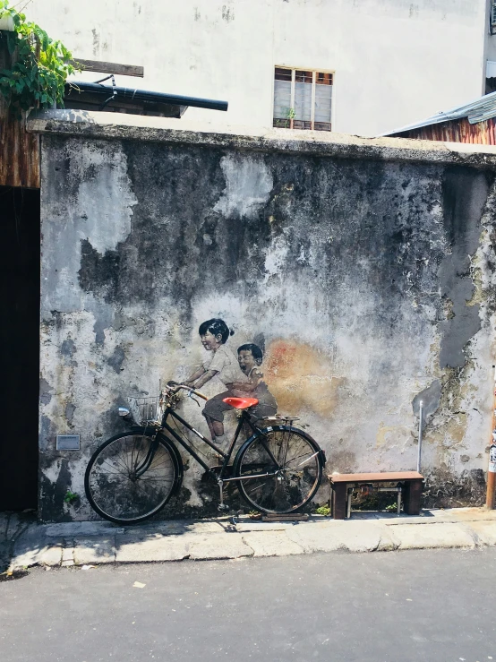 a bike leaning against a wall painted with children on it