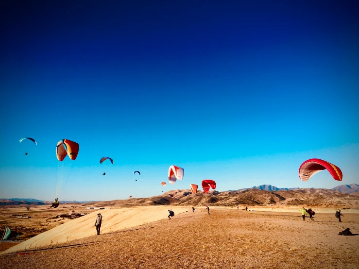 some people are flying kites in the desert