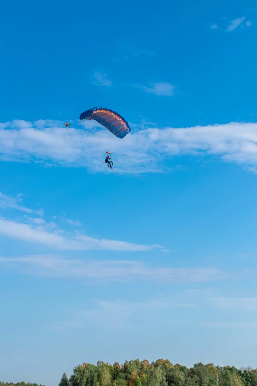 a man with a large parachute being held up by a small plane