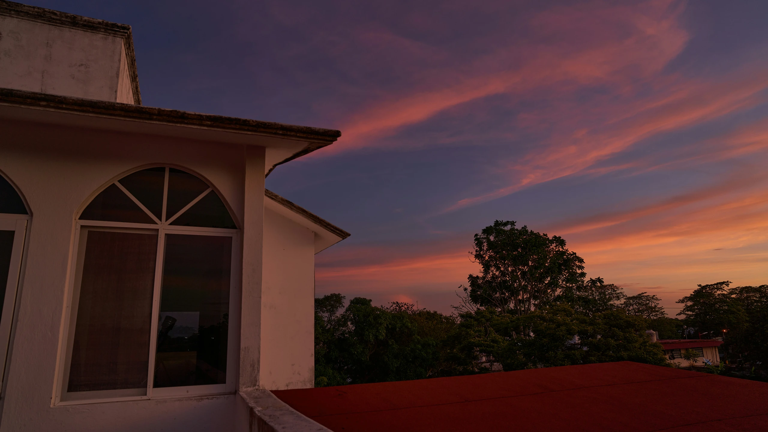 the sunset as seen from the front yard of a house