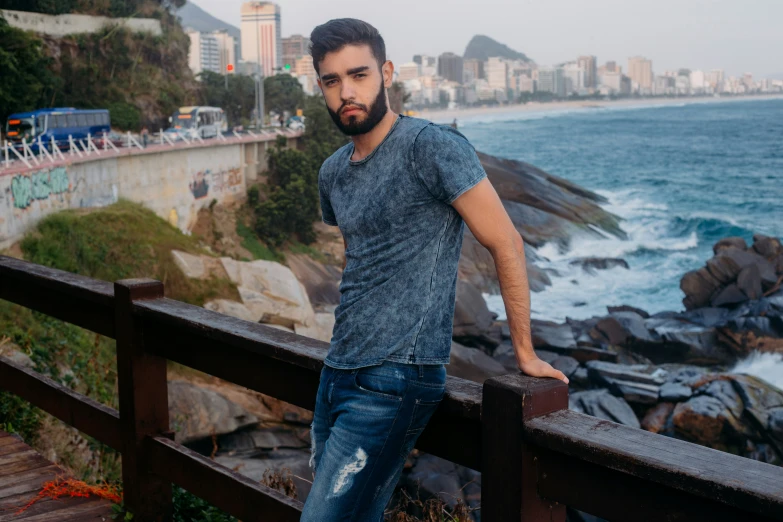 a man is leaning against the edge of a railing by the beach