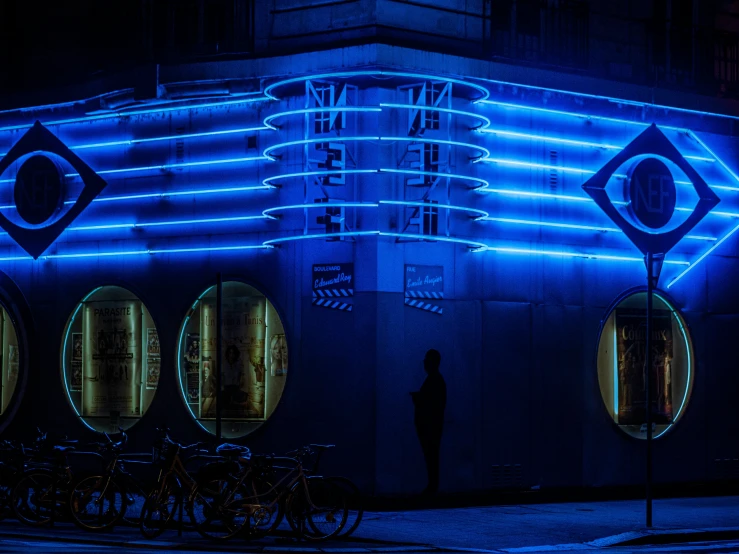 a blue lit building with bicycles parked next to it