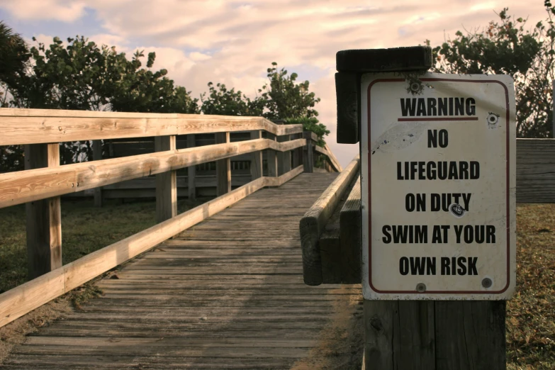 a wooden bridge with a warning sign over it
