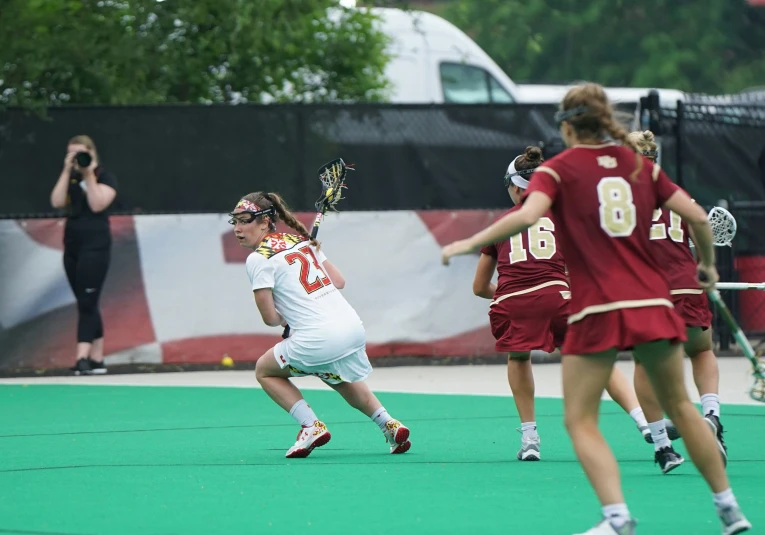 two teams playing hockey in the field, one with a red uniform