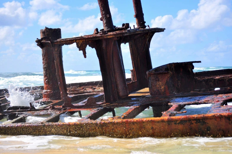 an old rusted boat sitting on top of the ocean