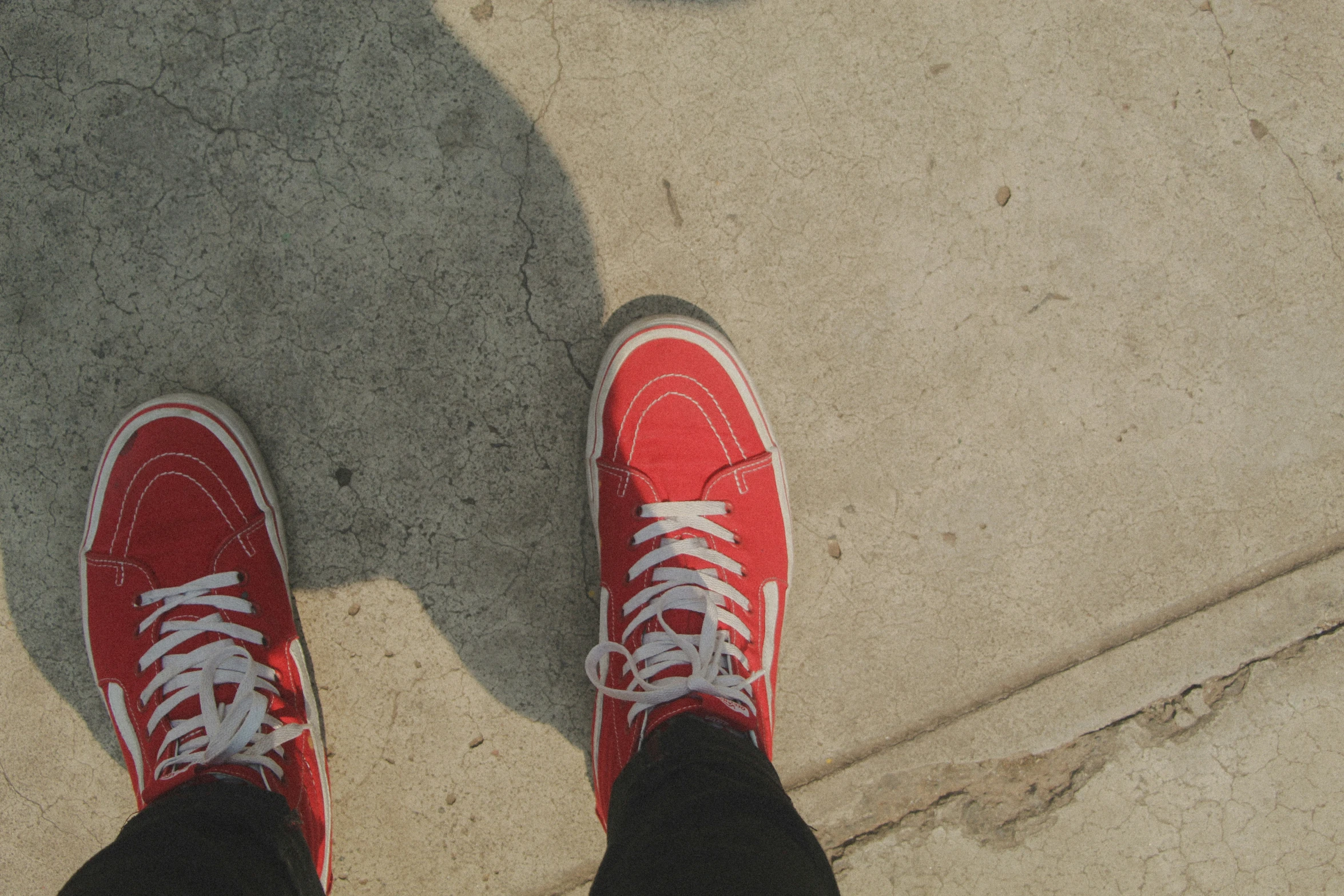 shoes on the ground looking down with their shadow on it