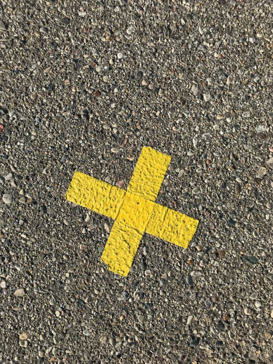 a painted yellow cross on the ground in a street