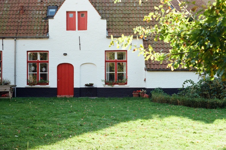 a building with three red windows and grass