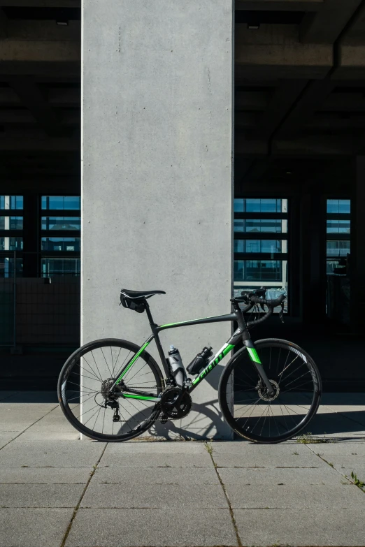 green and black bicycle leaning up against white column
