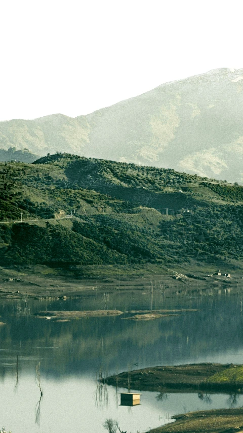 a boat floating on the river in front of a hill