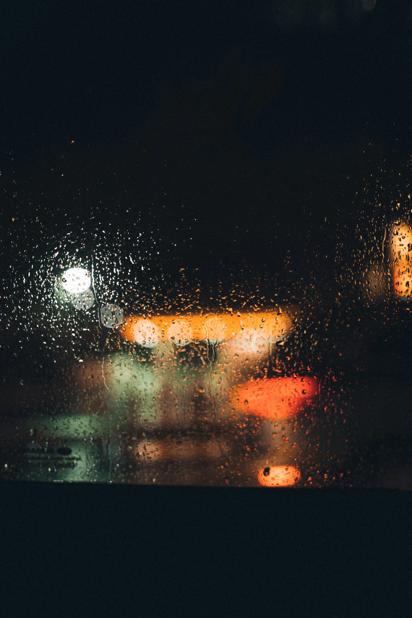 city street view through rain covered window at night