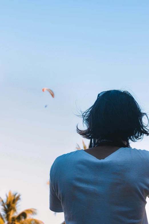 a person standing on top of a grass covered hillside flying a kite