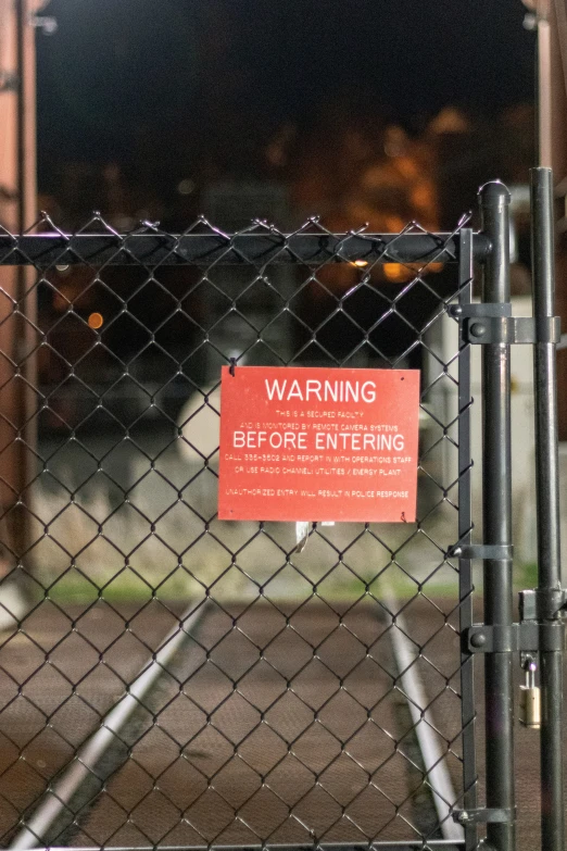 the back fence of a baseball field next to a red sign on it