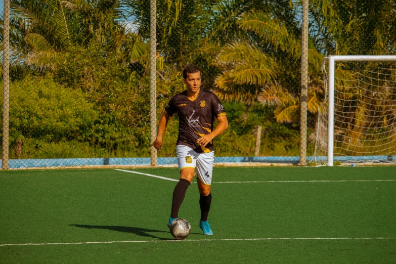 a soccer player wearing a maroon shirt and white shorts, prepares to kick the ball on the field