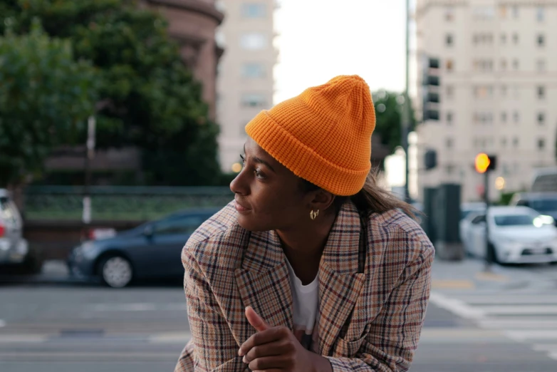 a women with orange hat leaning up against the side of a traffic light