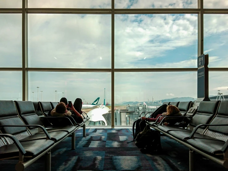 a pair of people sitting on top of airport chairs