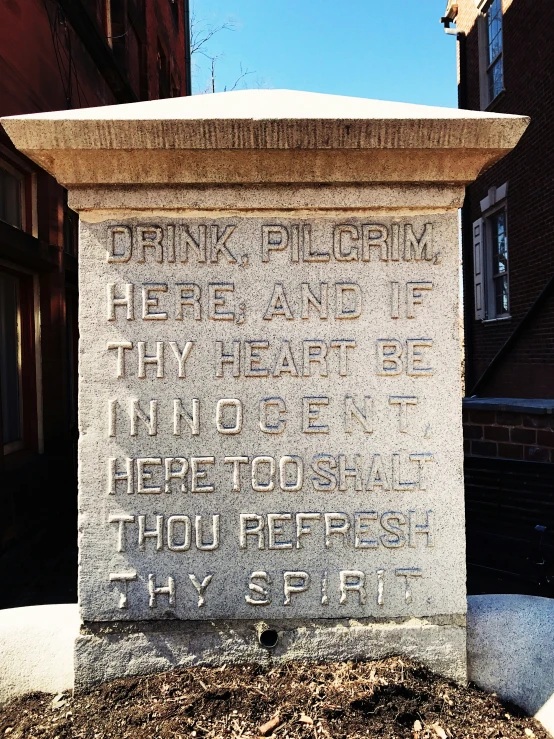 a stone monument with text written on it and building behind
