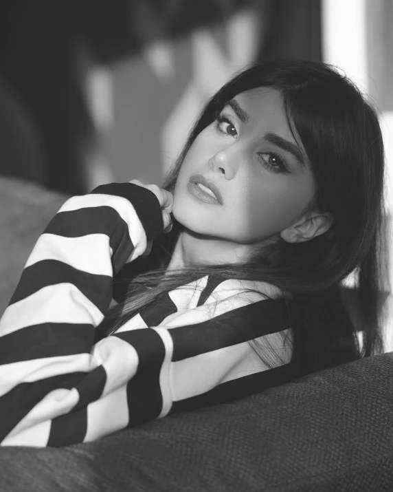 young woman sitting on sofa posing for black and white