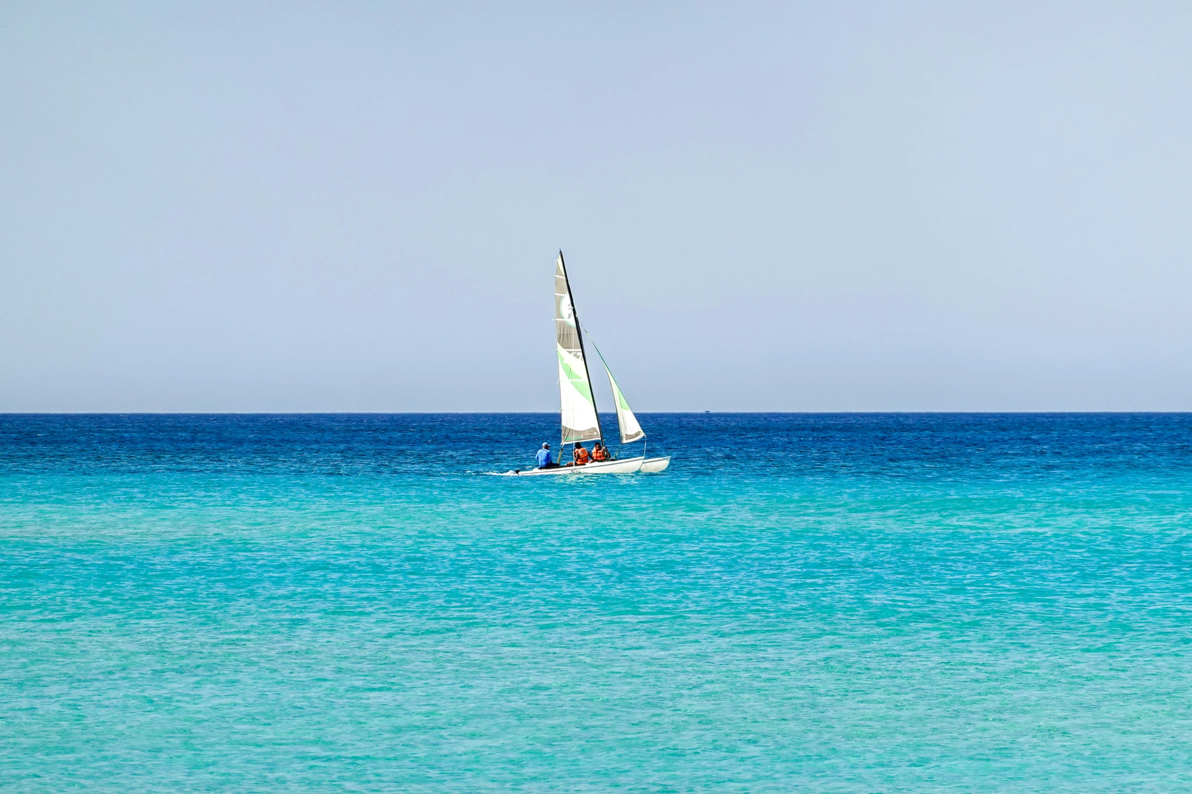 a sailboat floats on clear blue water