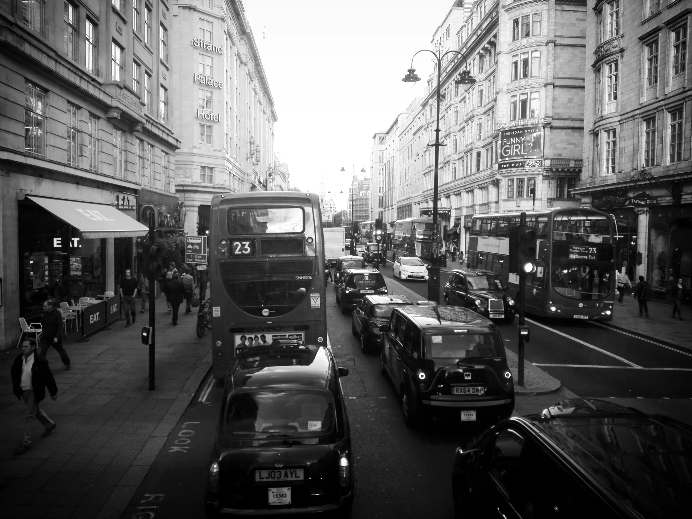 several buses, cars, and pedestrians on a busy street