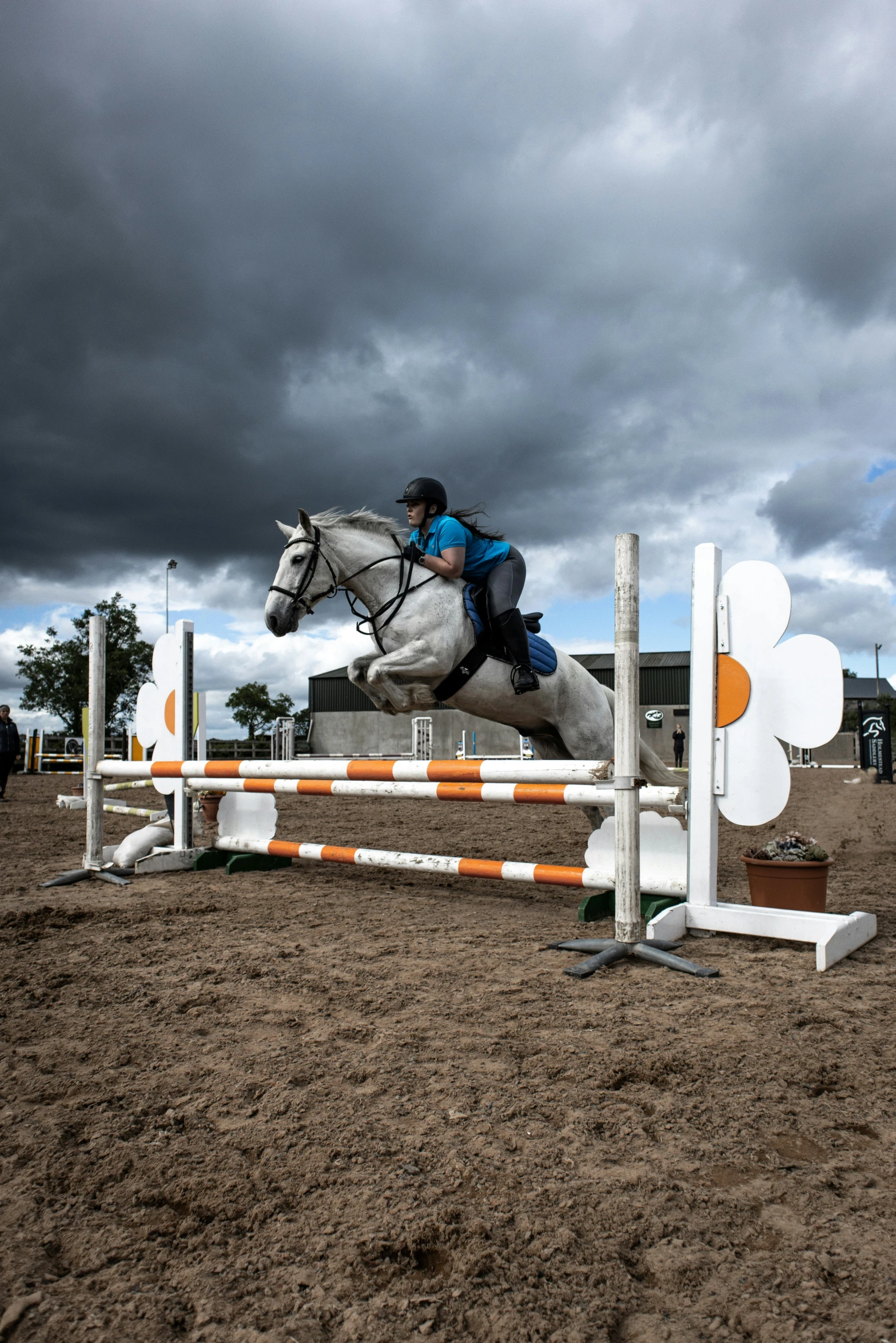 a person riding on the back of a white horse jumping over an obstacle