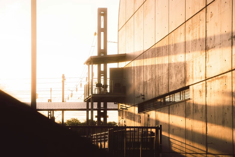 a building with pipes coming out of it with the sun rising over the wall behind it