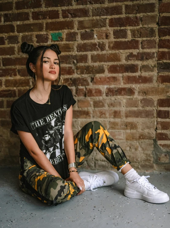 a woman sitting on the ground in camo pants