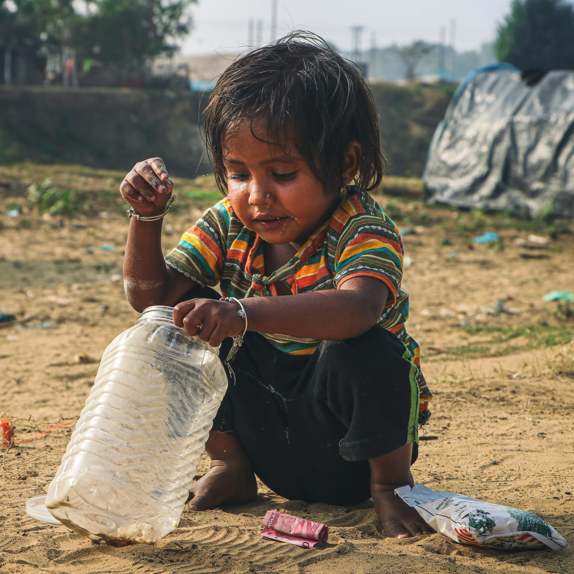 a girl playing with a container in the sand