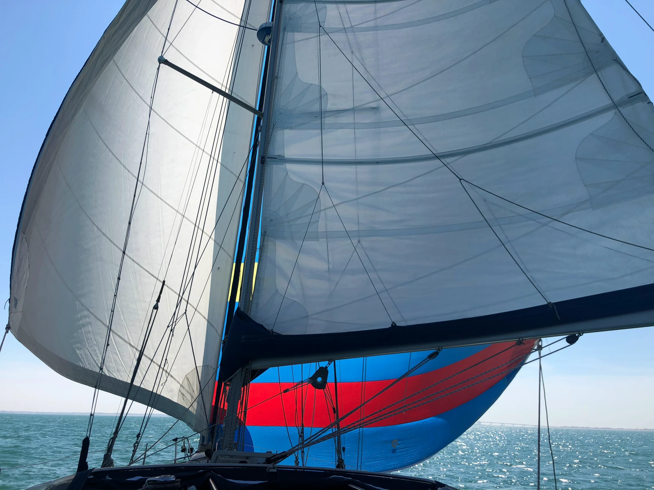 a sailboat sailing across the water with a blue and red stripe