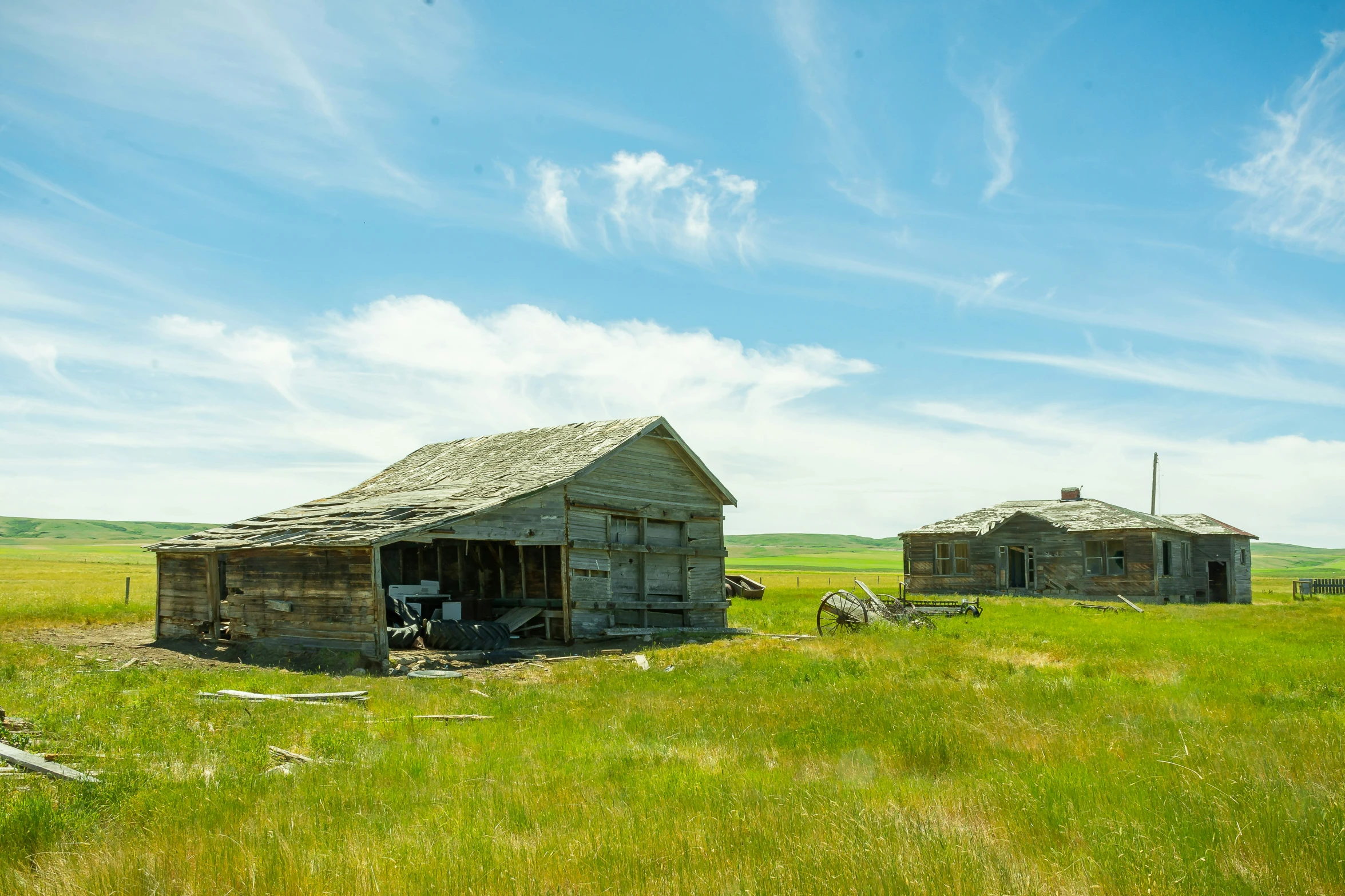 two abandoned farm buildings in an open green field