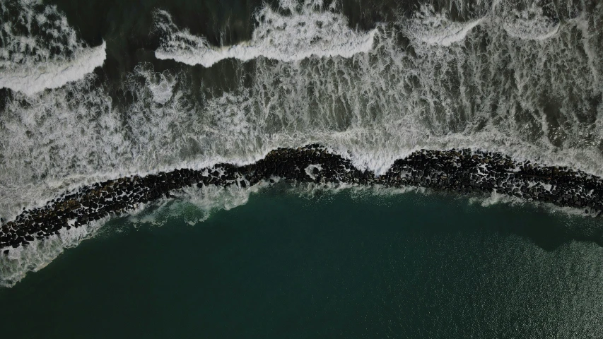 an aerial view of a wave crashing over the shoreline