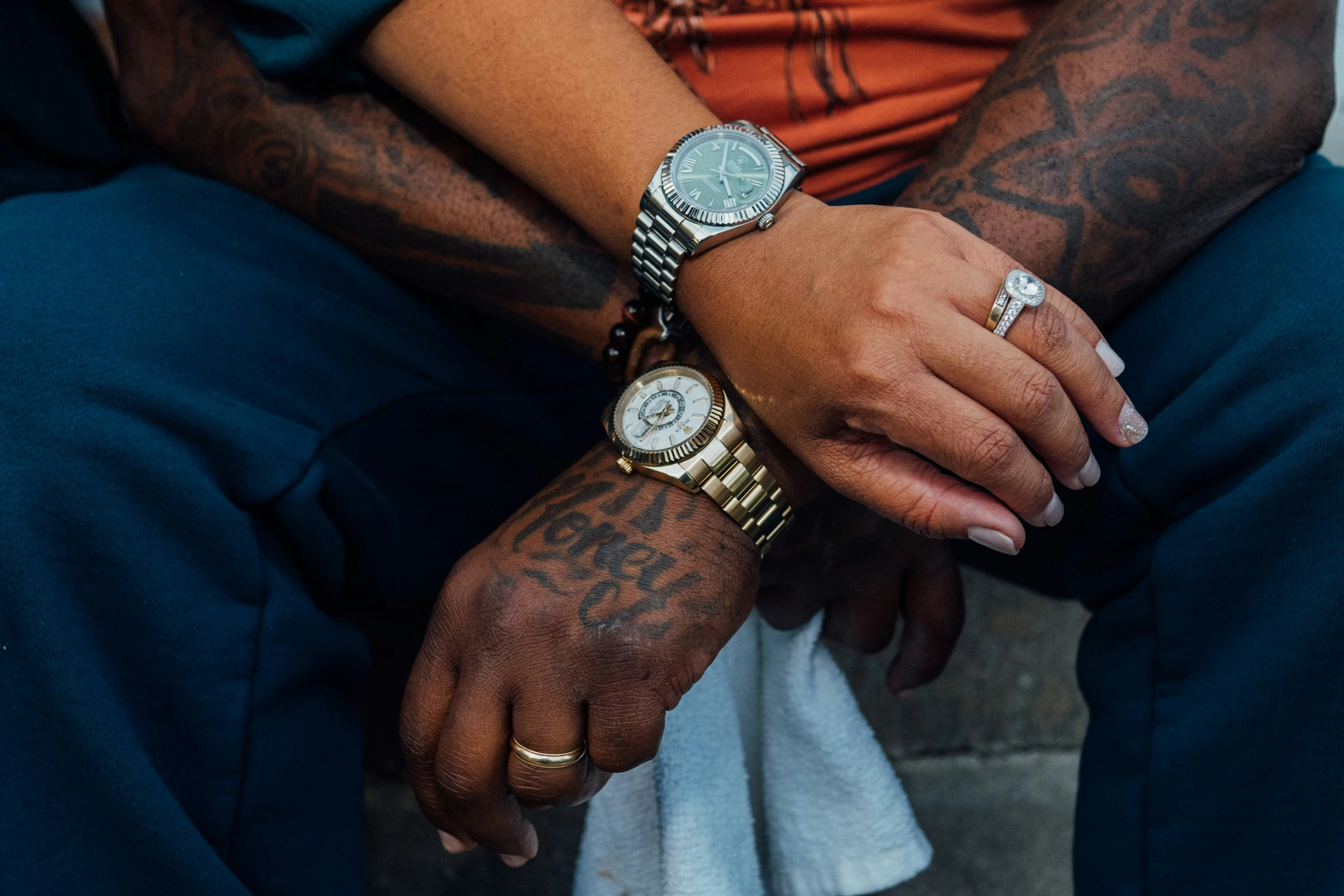 two tattooed people hold hands on their wrists